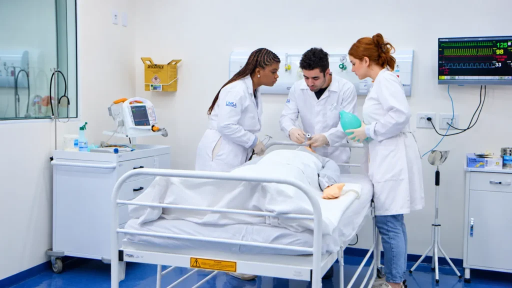 procedimento de simulação de emergência em um boneco, em uma sala hospitalar equipada com monitores e aparelhos médicos.