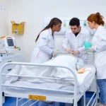 procedimento de simulação de emergência em um boneco, em uma sala hospitalar equipada com monitores e aparelhos médicos.